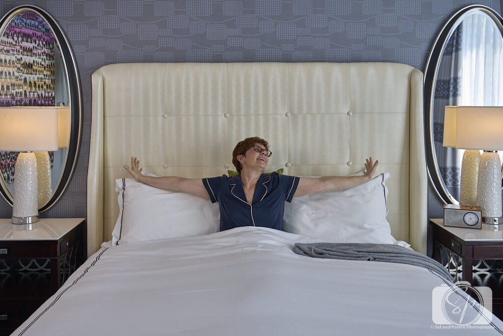 Andi in bed at the Kimpton Tryon Park Hotel with Quince Silk Pajamas