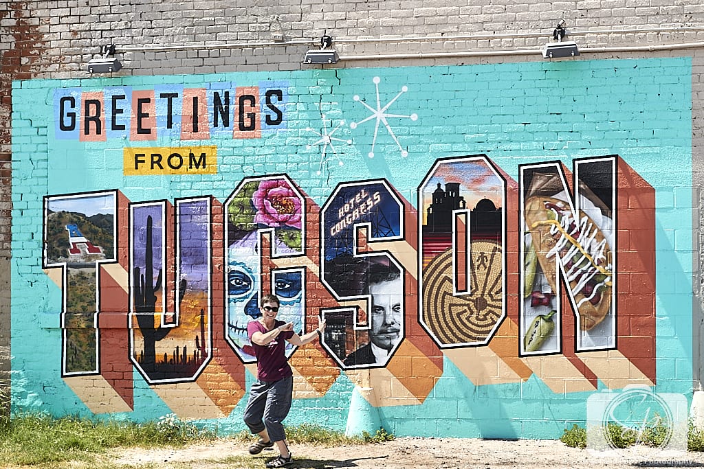 Andi in front of Tucson Greetings Mural by Rock Martinez and Victor Ving