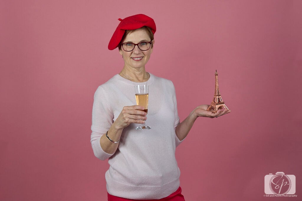 Andi in Quince sweater and beret with glass of champagne and eiffel tower