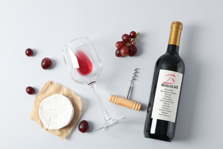 red wine bottle, grapes, cheese and wine glass