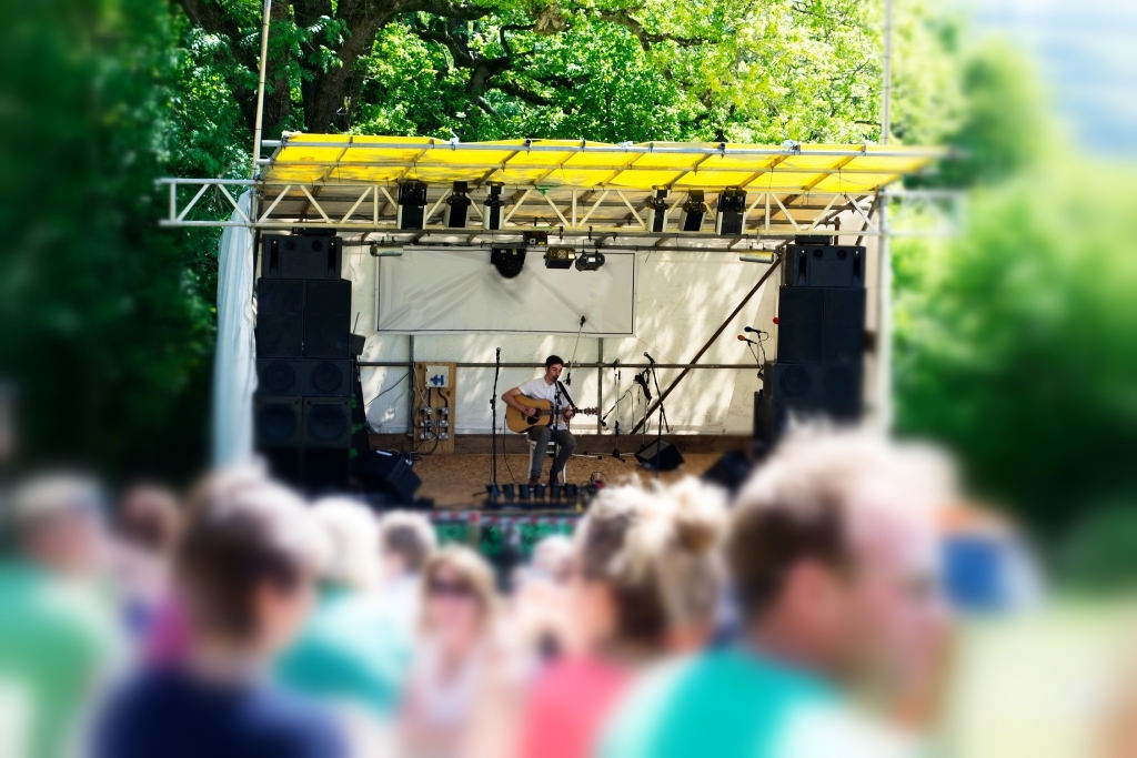 man performing with guitar at an outdoor festival