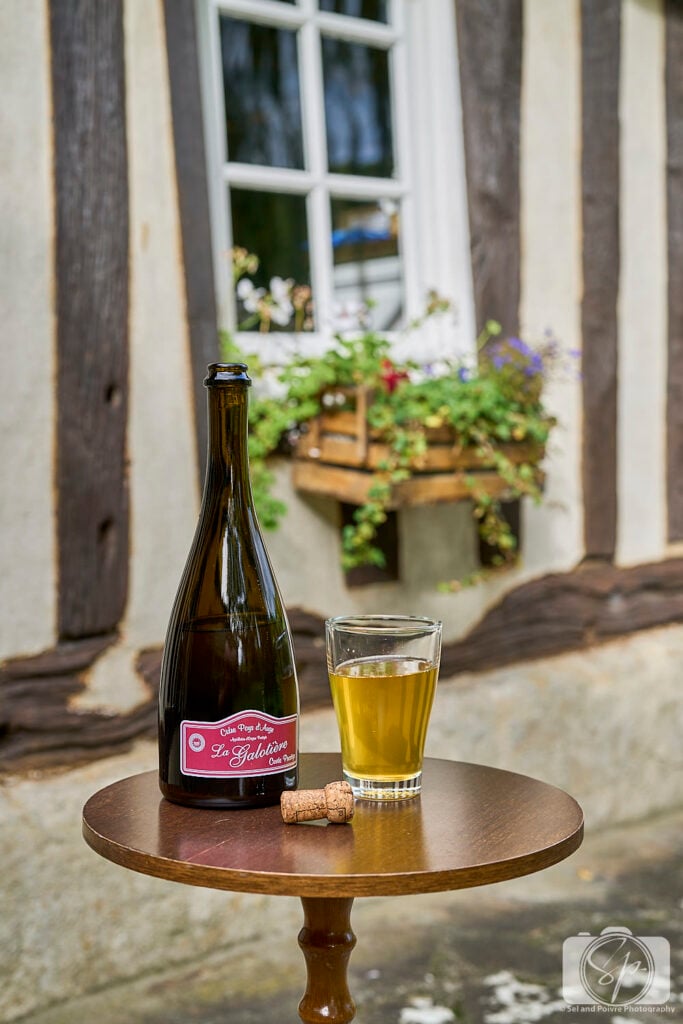 Pays D'Auge Normandy France Cider Bottle with a Glass in front of Normand House
