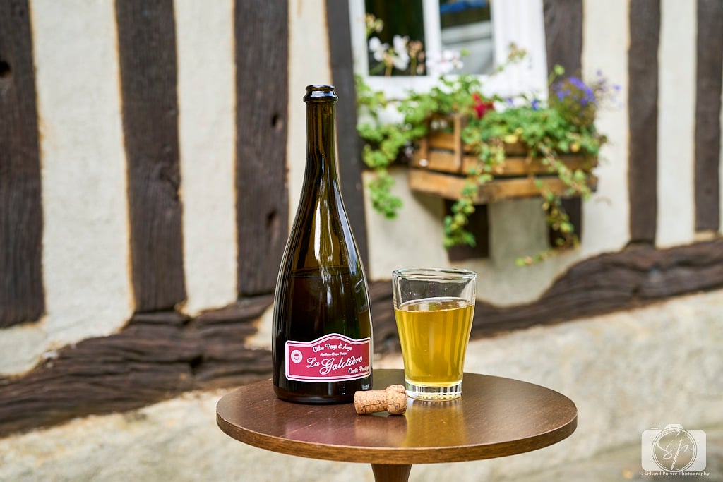Pays D'Auge Normandy France Cider Bottle with a Glass in front of Normand House