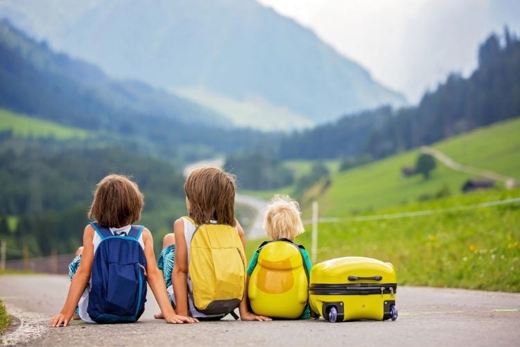 3 kids sitting on the road with backpacks