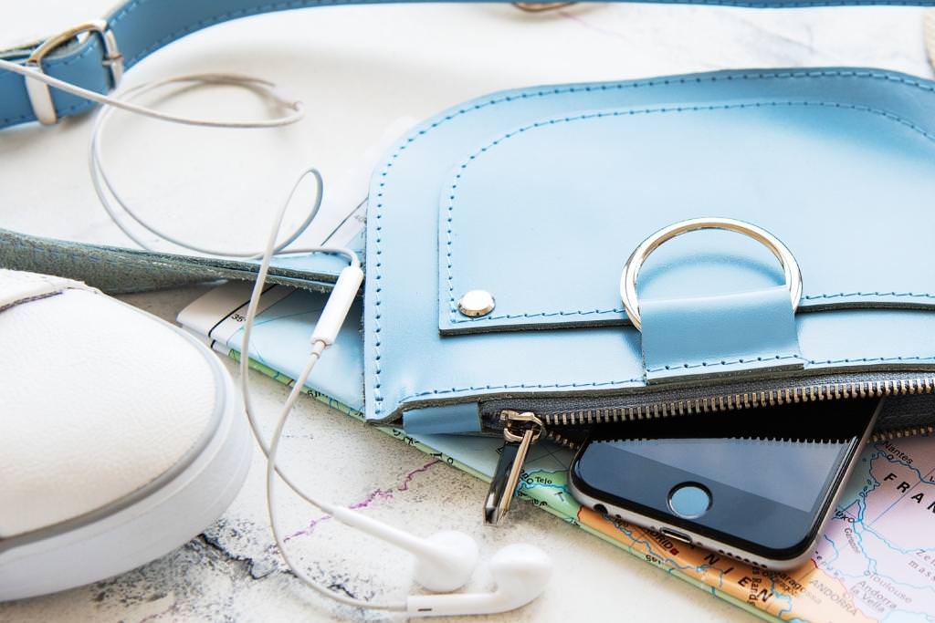 blue travel wallet with map and white tennis shoe