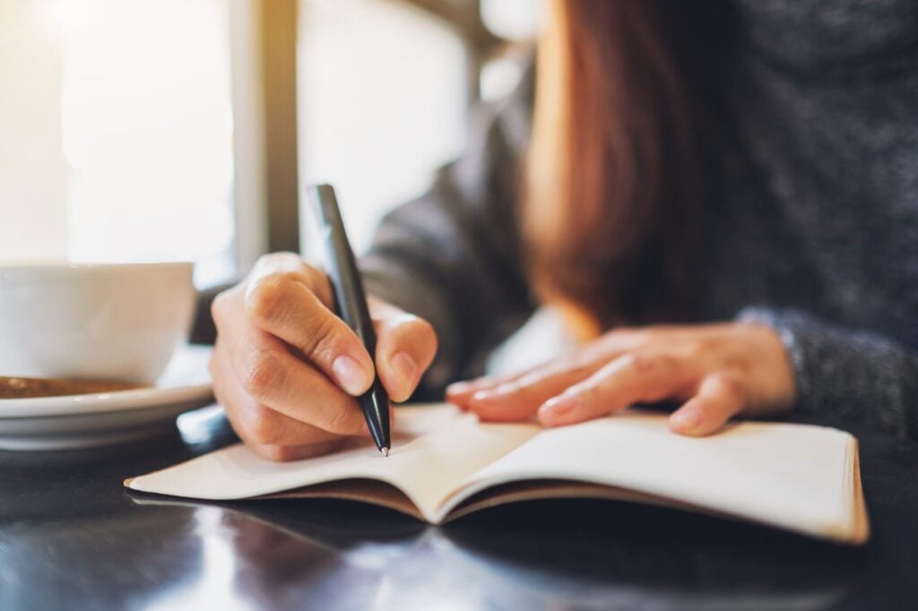 woman writing in notebook in coffee shop