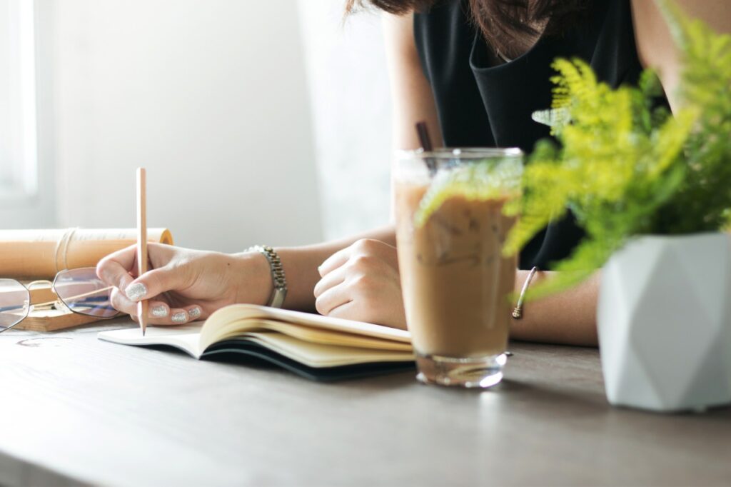 woman writing in notebook in coffee shop