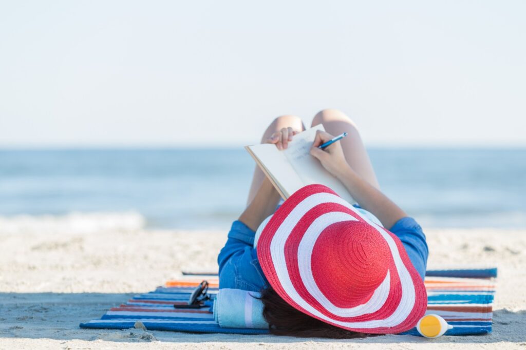 woman writing in notebook on the beach
